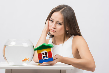 Image showing She knocks on the wall of the house a toy aquarium with goldfish