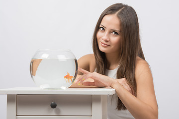 Image showing The girl points a finger at aquarium with goldfish