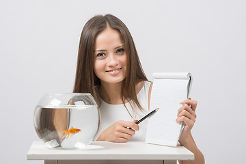 Image showing Girl shows a pen entry pad, standing next to an aquarium with goldfish