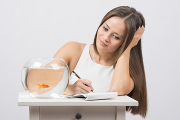 Image showing Girl writing in a notebook desire to fulfill a goldfish