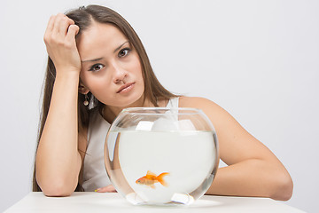 Image showing Upset young girl sitting next to the fishbowl