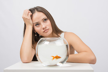 Image showing Thoughtful young girl looking at goldfish in a fishbowl