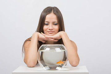 Image showing Beautiful girl looks at the aquarium presented with goldfish