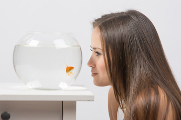 Image showing Young girl leaning face to the aquarium and looking at goldfish