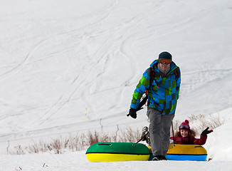 Image showing Father and daughter with snow tube at sun day