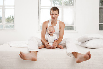 Image showing young father with his nine months old son on the bed at home