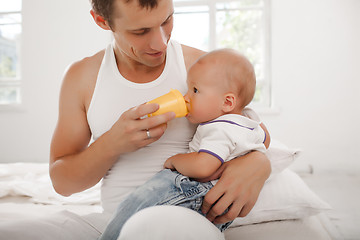 Image showing Young father with his nine months old son on the bed at home