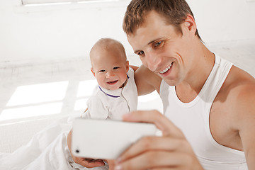 Image showing young father with his nine months old son on the bed at home