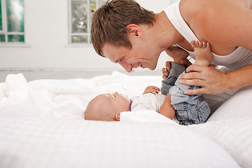 Image showing young father with his nine months old son on the bed at home