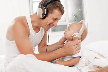 Image showing young father with his nine months old som on the bed at home