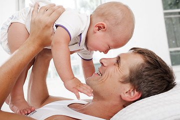 Image showing young father with his nine months old son on the bed at home