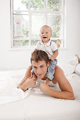 Image showing young father with his nine months old son on the bed at home