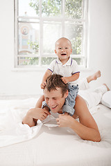 Image showing young father with his nine months old son on the bed at home