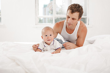 Image showing young father with his nine months old son on the bed at home