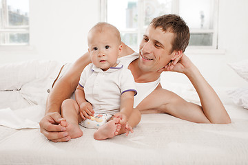 Image showing young father with his nine months old son on the bed at home