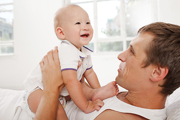 Image showing young father with his nine months old son on the bed at home