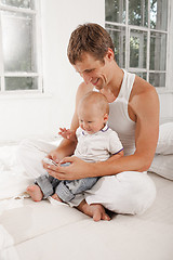 Image showing young father with his nine months old son on the bed at home