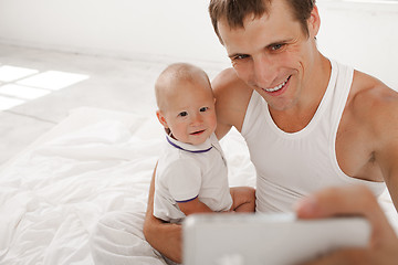 Image showing young father with his nine months old son on the bed at home