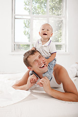 Image showing young father with his nine months old son on the bed at home