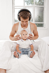 Image showing young father with his nine months old som on the bed at home