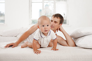 Image showing young father with his nine months old son on the bed at home