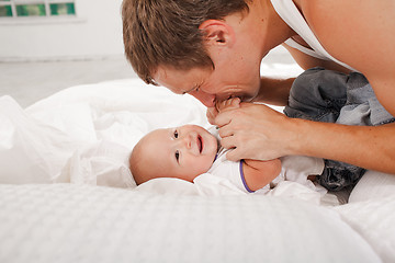 Image showing young father with his nine months old son on the bed at home