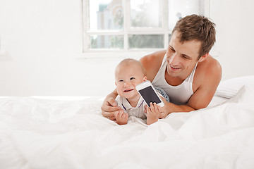 Image showing young father with his nine months old son on the bed at home