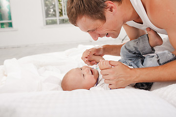 Image showing young father with his nine months old son on the bed at home