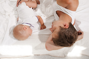 Image showing young father with his nine months old son on the bed at home