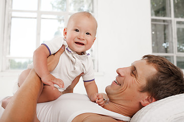 Image showing young father with his nine months old son on the bed at home