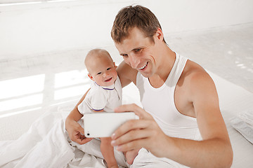 Image showing young father with his nine months old son on the bed at home