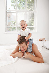 Image showing young father with his nine months old son on the bed at home