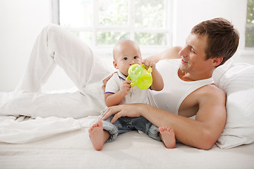 Image showing Young father with his nine months old son on the bed at home