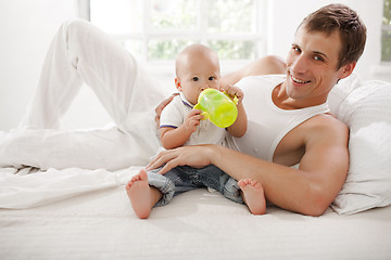 Image showing Young father with his nine months old son on the bed at home