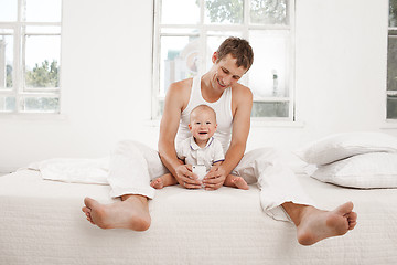 Image showing young father with his nine months old son on the bed at home