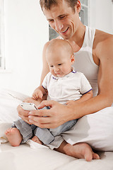 Image showing young father with his nine months old son on the bed at home