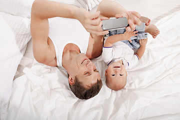 Image showing young father with his nine months old son on the bed at home