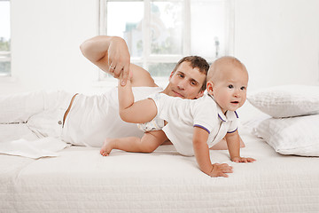 Image showing young father with his nine months old son on the bed at home