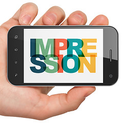 Image showing Marketing concept: Hand Holding Smartphone with Impression on  display