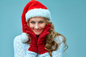 Image showing The happy girl dressed in santa hat. Holiday concept with blue background.