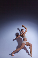 Image showing Young beautiful dancer in beige swimwear dancing on lilac background