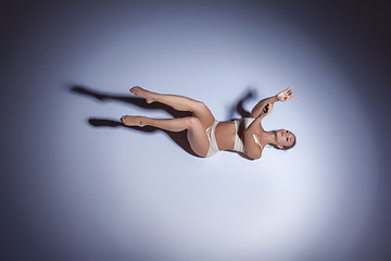 Image showing Young beautiful dancer in beige swimwear dancing on lilac background