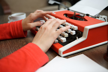 Image showing human hands writing on red typewriter