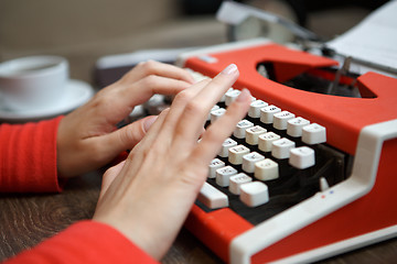 Image showing human hands writing on red typewriter