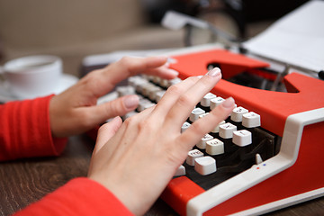 Image showing human hands writing on red typewriter