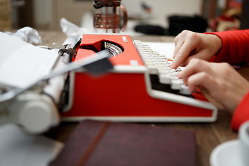 Image showing woman at table typing on typewriter