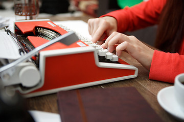 Image showing woman at table typing on typewriter