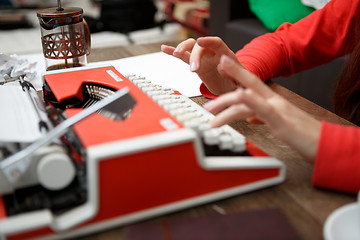 Image showing woman at table typing on typewriter