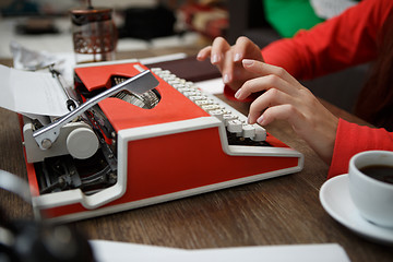 Image showing woman at table typing on typewriter