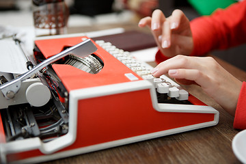 Image showing woman at table typing on typewriter